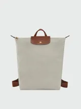 Mochila Longchamp modelo Le Pliage Original tamaño M, de color negro con detalles en cuero marrón y herrajes dorados. Cuenta con solapa con botón a presión, cierre superior y correas ajustables.