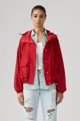Campera parka roja estilo blouson con capucha ajustable, cierre frontal de botones a presión, bolsillos frontales con solapa y diseño holgado.