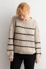 Sweater de punto con textura, color beige melange con rayas horizontales negras. Presenta cuello redondo, mangas largas y corte holgado.