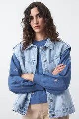 Chaleco de jean en tono celeste claro, con corte recto, cuello camisero, cierre frontal con botones metálicos y costuras visibles.