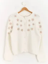 Cardigan de punto color blanco con diseño de flores bordadas en tono beige, cuello redondo, cierre frontal con botones forrados y mangas largas.