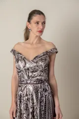 Vestido largo de satén de seda estampado en tonos chocolate y natural, con escote off-shoulder y falda con movimiento. Incluye lazo para ajustar la cintura y tul transparente en el escote.
