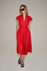 Vestido midi rojo de la colección ZW de Zara, confeccionado en hilatura con lino. Cuenta con escote en pico, manga corta, bolsillos laterales ocultos en la costura, falda de corte evasé y cierre frontal con cinturón ajustable del mismo tejido.