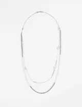 Collar largo doble plateado con cadena de eslabones finos y cadena de eslabones cuadrados. El collar más corto tiene cuentas plateadas y el más largo tiene cuentas plateadas y un dije cilíndrico.