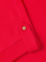 Remera de algodón de corte regular y cuello redondo, con mangas cortas que presentan un detalle de doblez con botón decorativo. Incluye el logo de la marca bordado en el pecho.