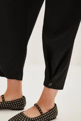 Pantalon de vestir negro de corte sastrero, con tiro medio, bolsillos laterales y botamanga con detalle de botón.