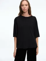 Remera de corte boxy y calce amplio, con cuello redondo y mangas cortas, de diseño minimalista y estructura relajada.