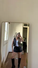 Chaleco corto de ecocuero color marrón oscuro, con corte ajustado y cierre frontal con broches metálicos.