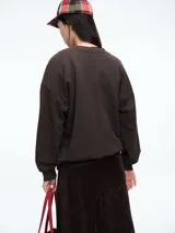 Buzo de algodón color gris oscuro, con cuello redondo, mangas largas y puños elásticos. Presenta la palabra LOVE estampada en el frente con aplicaciones de lentejuelas rojas.