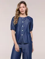 Blusa de calce relajado de lyocell en tono azul denim, con cuello a la base y cierre frontal de botones metálicos. Tiene mangas cortas abullonadas con puños elásticos.