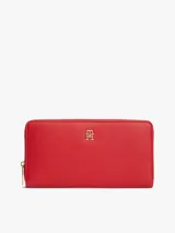 Billetera Tommy Hilfiger de color rojo con acabado granulado y cierre integral de cremallera. Presenta dos compartimentos principales, múltiples ranuras para tarjetas, un bolsillo interior con cremallera y el monograma TH metálico en la parte delantera.