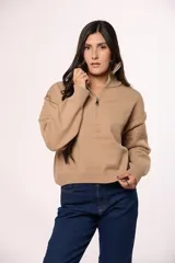Buzo tejido de punto con cuello alto y cierre frontal parcial. Presenta mangas largas con puños acanalados y un diseño de corte holgado.
