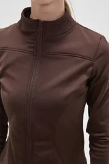 Campera deportiva de ajuste entallado, confeccionada en poliéster color gris oscuro. Presenta cuello alto, cierre frontal completo y mangas largas con aberturas para los pulgares.