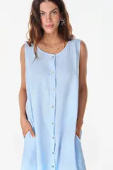 Vestido midi celeste de lino italiano, sin mangas, con escote redondo y cierre frontal abotonado con bolsillos laterales y corte holgado.