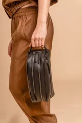 Neceser rectangular de símil cuero color beige claro, con dos compartimentos principales con cierre y un bolsillo frontal con cierre. Posee un asa lateral para transporte.