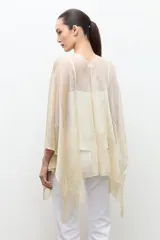 Ruana de tejido abierto con hilo de lurex dorado, diseño amplio y caída ligera.