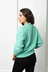 Buzo de lana color verde menta con diseño de tejido trenzado en relieve, cuello redondo y mangas largas con puños ajustados.