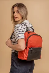 Mochila urbana de diseño combinado, confeccionada en tela resistente con bolsillo frontal y detalles en cuero sintético. Cuenta con compartimento principal con cierre y correas ajustables.