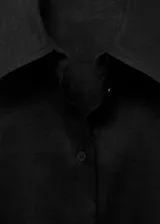 Camisa negra de manga corta, confeccionada en tejido de lino y algodón, con cuello camisero, diseño recto y cierre frontal de botones.