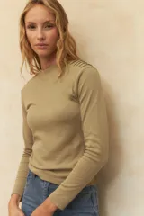 Polera de manga larga en color beige, confeccionada en algodón, con cuello alto y detalle de costuras decorativas en los hombros.