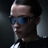 Lentes de sol envolventes con montura de acero inoxidable en acabado plateado cepillado y lentes de nylon espejadas. Presentan un diseño vanguardista con aberturas decorativas en la parte superior del marco.