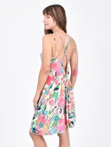 Vestido corto con estampado floral multicolor sobre fondo blanco, de escote en V y tirantes finos. Presenta un diseño entallado en el busto y falda con ligero vuelo.