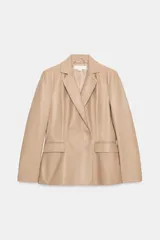 Blazer cruzado de efecto piel color bordó, con solapas de muesca, mangas largas y bolsillos con solapa en la parte delantera. Cierre frontal con botones a tono.