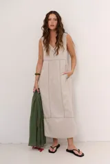 Vestido midi de lino color beige, sin mangas, con escote en V y costuras visibles a contratono.