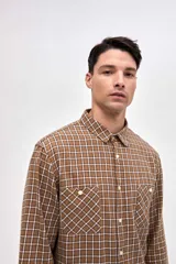 Camisa de corte regular fit confeccionada en algodón, con estampado de cuadros, cuello solapa clásico, cierre frontal con botones y dos bolsillos en el pecho.