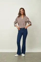 Jean de denim azul de corte flare, con tiro medio, diseño de botamanga acampanada y sutil estampado texturizado en toda la prenda.