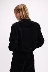 Chaqueta corta de terciopelo negro con efecto desgastado en tono azulado, cuello mao, cierre frontal metálico y bolsillos frontales con tapa y botón.