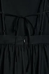 Vestido midi negro de escote recto con tirantes finos ajustables, espalda descubierta y falda amplia con bajo de bordados perforados a tono y detalle de puntilla.