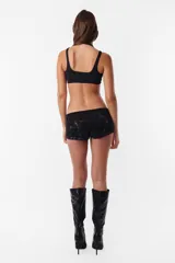 Microshort de gabardina de tiro bajo y corte slim fit. Presenta costuras en contraste color rojo, cierre metálico frontal y presillas largas en la cintura. La prenda cuenta con un proceso de sobreteñido y lavado artesanal que le otorga un aspecto desgastado único.