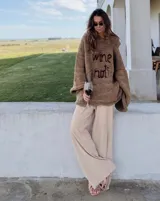 Sweater de lana merino tejido a mano, color marrón, con diseño oversize, mangas anchas y frase bordada en el frente.