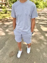 Conjunto deportivo gris melange compuesto por remera de manga corta y short con cordón ajustable en la cintura.