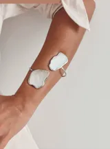 Brazalete rígido abierto de alpaca plateada con dos piezas irregulares de nácar blanco.