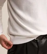 Suéter negro de tejido de punto maquinetado con cuello redondo y manga larga.