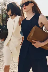 Bolso de hombro de piel color tostado, con detalle de costuras verticales pespunteadas en el cuerpo, doble asa de hombro y cierre con botones imantados.