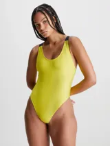 Malla enteriza Calvin Klein de textura acanalada brillante, color amarillo neón. Presenta cuello redondo, espalda amplia y tirantes elásticos negros con el logo de la marca. Incluye copas moldeadas suaves con relleno extraíble.