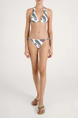 Calzón de bikini con tiras laterales ajustables y diseño estampado con patrón paisley en tonos azules, marrones y naranjas sobre fondo blanco. Cuenta con apliques metálicos decorativos en los cordones.