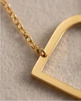 Collar de acero con baño de oro, compuesto por una cadena fina y un dije de corazón calado en relieve.