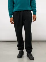 Pantalón de jogging de felpa con friza, color gris, con cintura elástica, bolsillos laterales y puños en los tobillos. Presenta un parche con el logo de Umbro en la parte superior delantera.