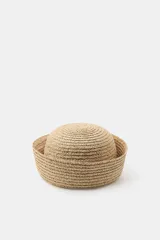 Sombrero de rafia 100%, de diseño tipo casquete con ala vuelta y tejido texturizado en tono tostado.