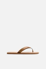 Sandalia plana color tostado, con dos tiras de cuero en el empeine y plantilla acolchada.