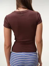 Remera blanca de manga corta y cuello redondo, confeccionada en tejido rib texturizado con corte entallado al cuerpo.