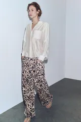 Camisa de cuello solapa y escote en pico, confeccionada en tejido satinado color marrón oscuro. Presenta manga larga con puños, cierre frontal con botones y un bolsillo plastrón en el delantero con detalle de bordado a tono.