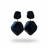Caravanas artesanales de diseño colgante, compuestas por un cabezal con textura que imita piedra y una pieza inferior geométrica de resina lisa, ambas en color negro.