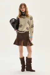 Sweater de tejido de punto color beige con estampado de flores oscuras, cuello redondo, manga larga con puño en contraste y bordado en el pecho.