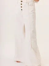 Pantalón ancho de mujer, estilo patchwork, combinando paneles de tela en tonos beige claro, beige medio y marrón. Presenta cierre frontal de botones y costuras contrastantes en rojo.