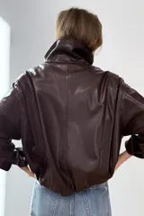 Chaqueta de efecto piel en color bordó, con cuello subido, manga larga con puños y bajo elástico. Presenta cierre frontal con cremallera y botones a presión ocultos, además de bolsillos laterales.